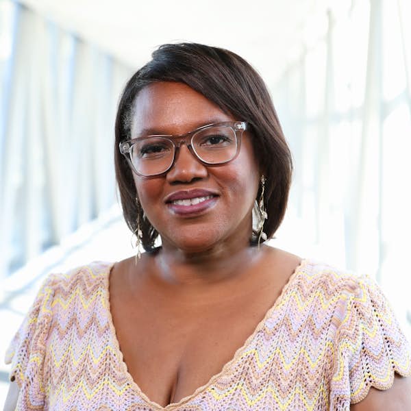 A person wearing glasses and a cream colored shirt