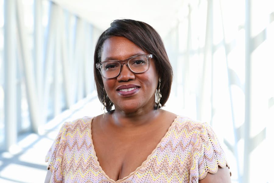 A person wearing glasses and a cream colored shirt